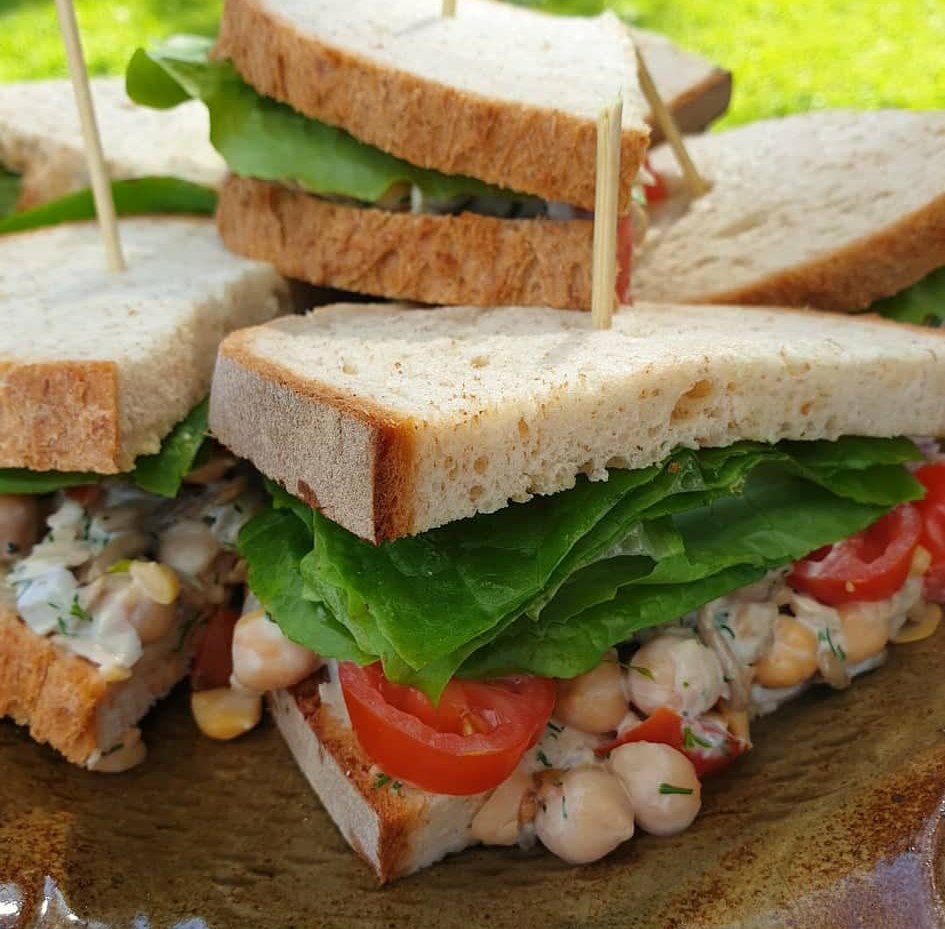 A pile of chickpea sandwiches on a plate with grass in the background